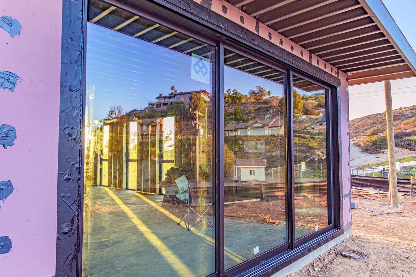 All Weather Architectural Aluminum sliding glass doors and windows installed at the Escondido Residence, reflecting the hillside view at sunset