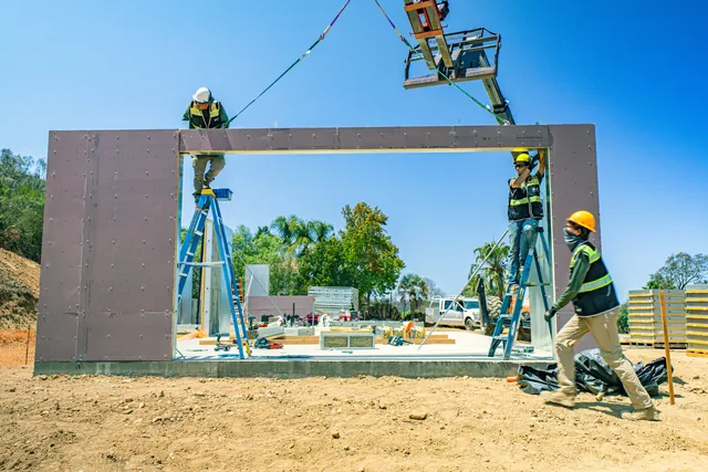 4C crew guiding a wall panel with a large opening into place at the Escondido Residence as a telehandler lowers it
