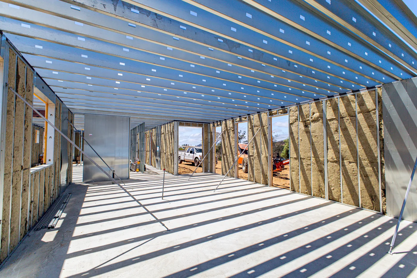 Interior view down the framed hallway of the Escondido Residence, roof trusses and door openings installed