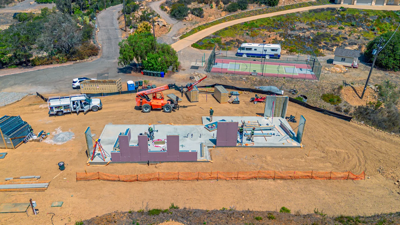 Aerial view of the Escondido Residence with SAFE wall panels rising on the foundation slab, telehandler staged on site